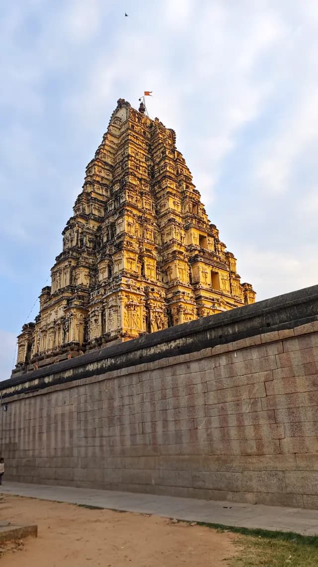 A towering, ornately carved temple gopuram rising above an old stone wall