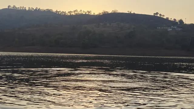 A lake at sunset with golden light over dark wooded hills